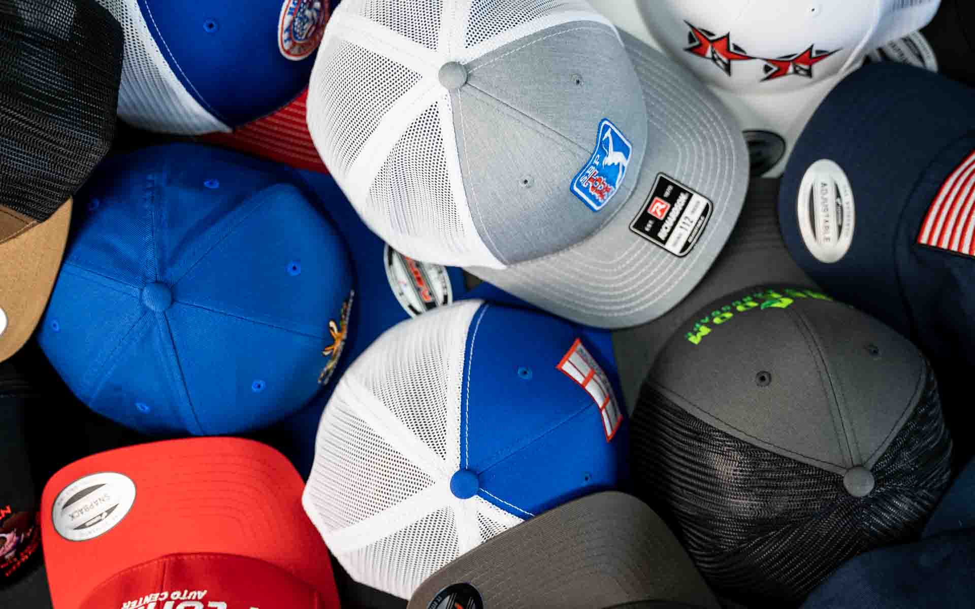 Stack of HatLaunch custom embroidered hats in assorted colors